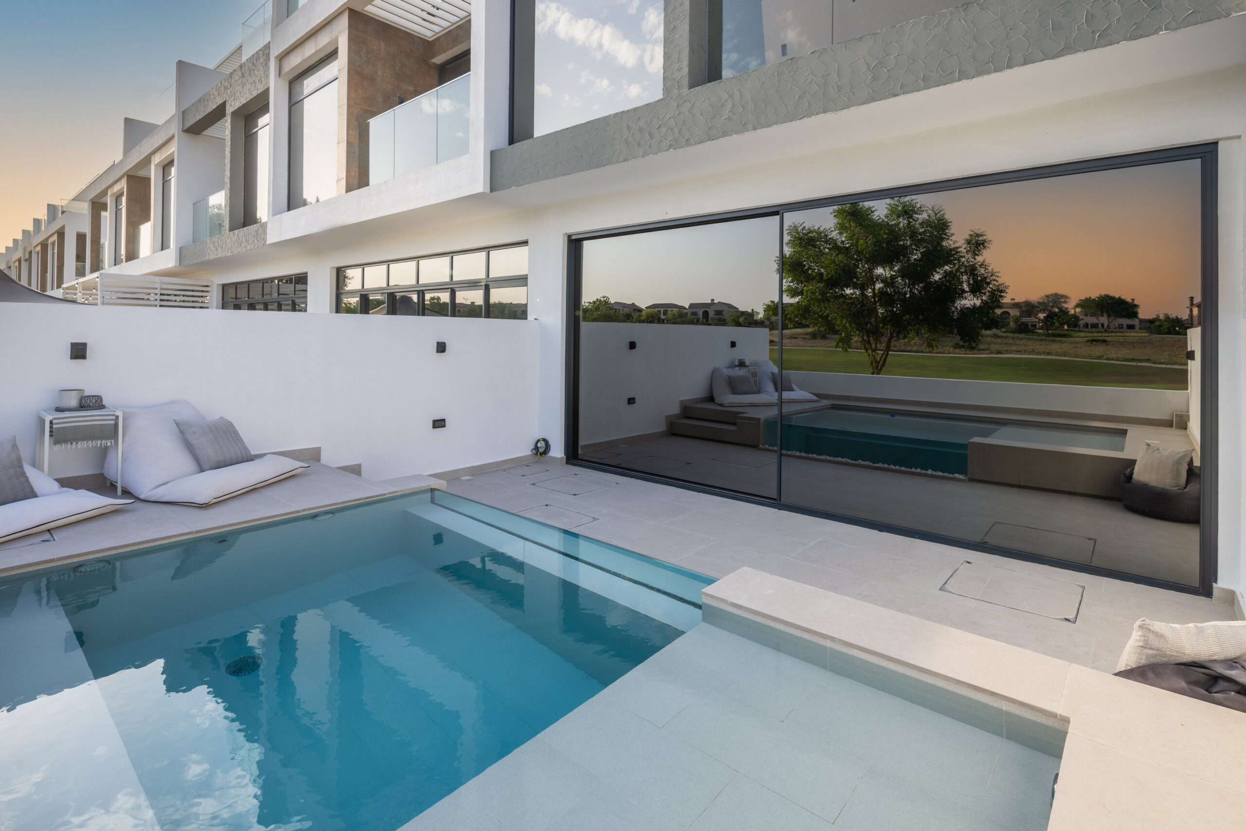 Renovated Dubai villa with a swimming pool and large black-framed glass doors overlooking the outdoor terrace.